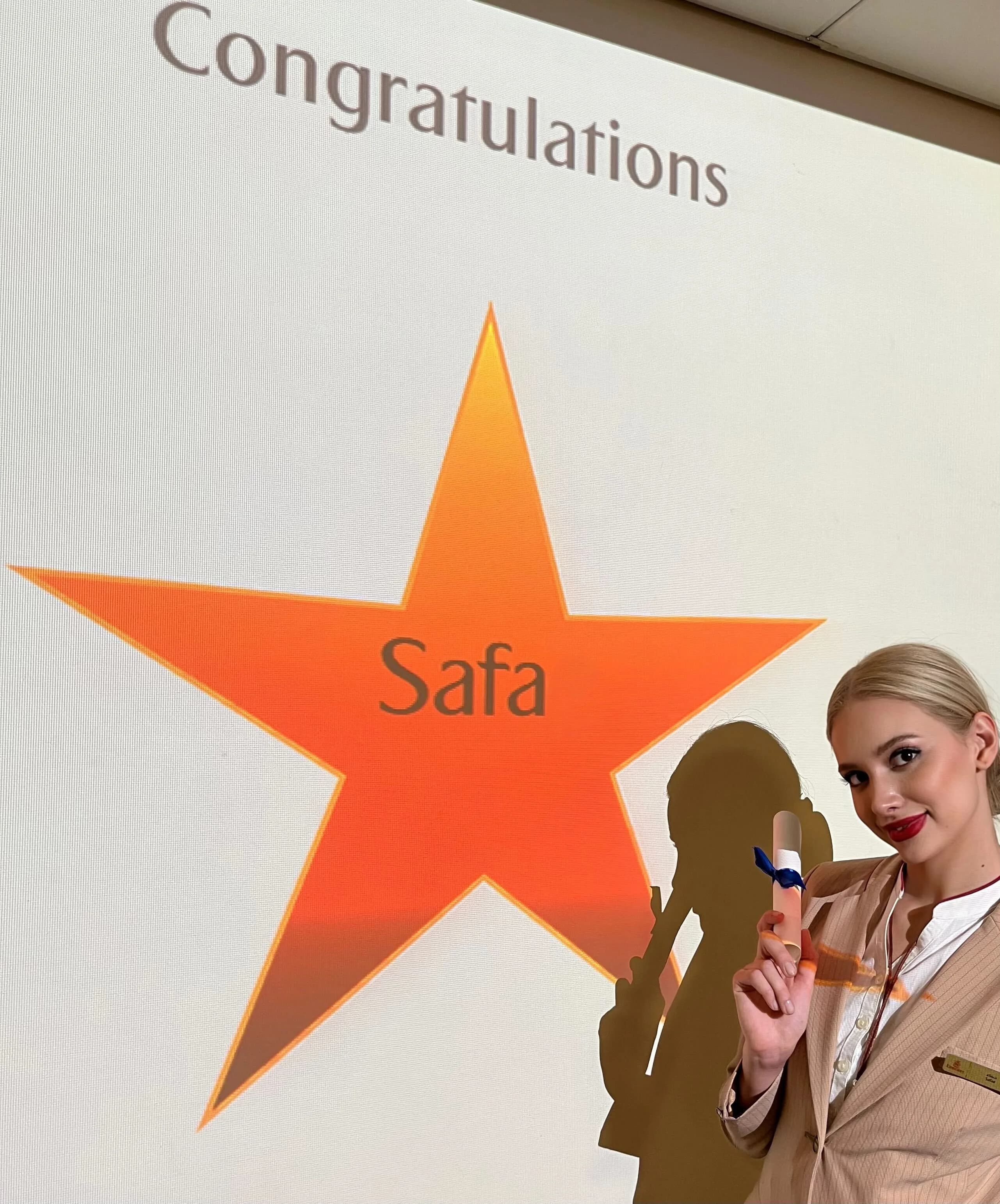Safae smiling beside a Congratulations board with her name on a gold star